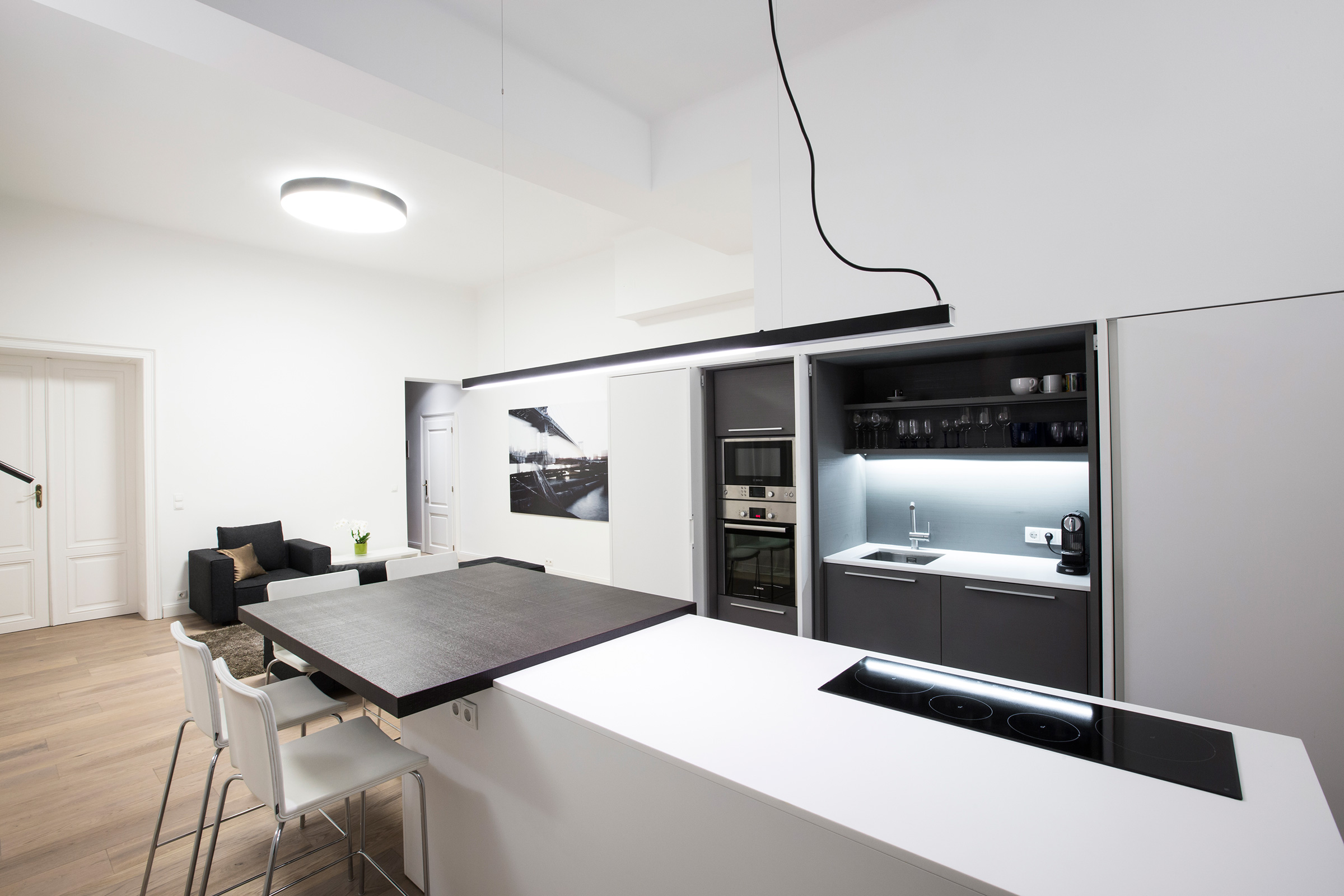 Modern open-plan kitchen and dining area with white island, dark wood table and designer chairs